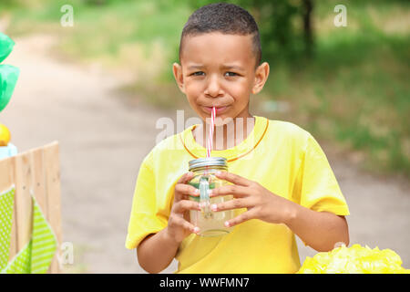 Cute little African-American boy drinking lemonade in park Stock Photo