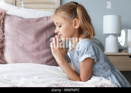 Cute little girl praying in bedroom Stock Photo