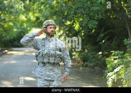 Saluting soldier in camouflage outdoors Stock Photo