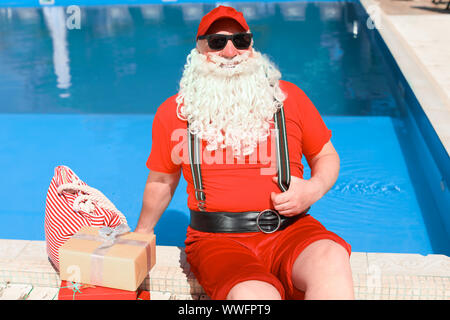 Santa Claus with gifts near swimming pool at resort Stock Photo