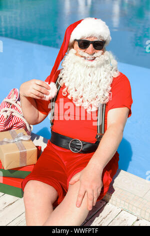 Santa Claus with gifts near swimming pool at resort Stock Photo