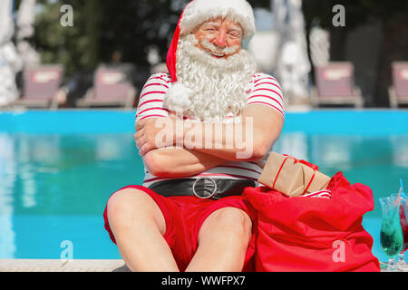 Santa Claus with gifts near swimming pool at resort Stock Photo