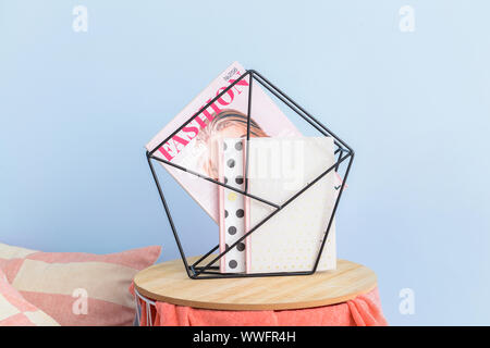 Stylish holder with books and magazine on table in room Stock Photo