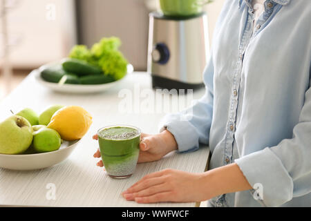 Woman with glass of tasty green smoothie in kitchen Stock Photo