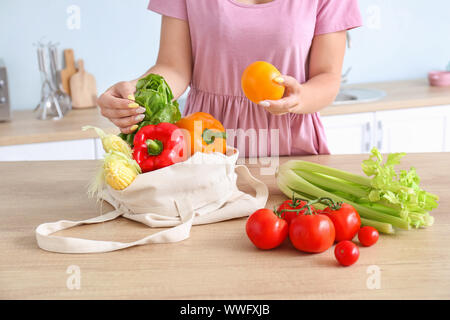 Woman taking products out of eco bag in kitchen Stock Photo