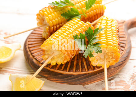 Tasty grilled corn cobs on wooden board Stock Photo
