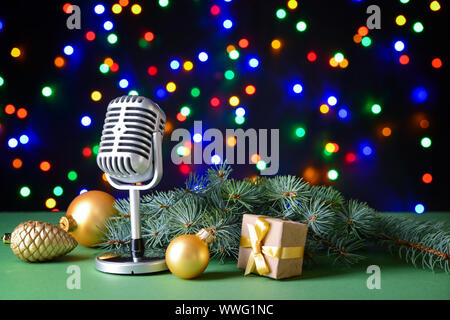 Retro microphone with Christmas decor on table against defocused lights Stock Photo