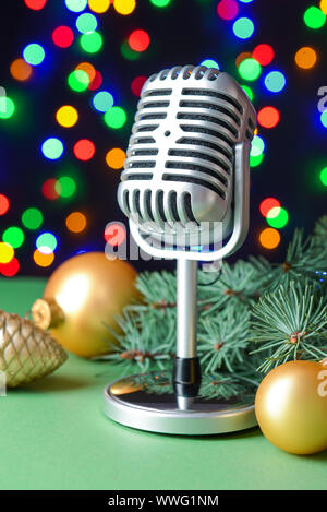 Retro microphone with Christmas decor on table against defocused lights Stock Photo