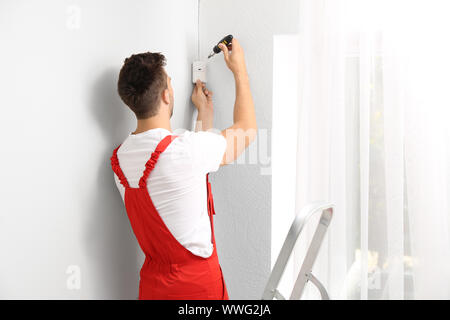 Electrician installing alarm system indoors Stock Photo