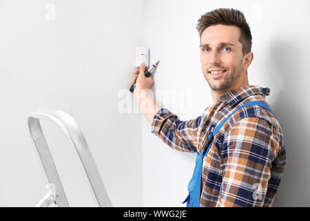 Electrician installing alarm system indoors Stock Photo