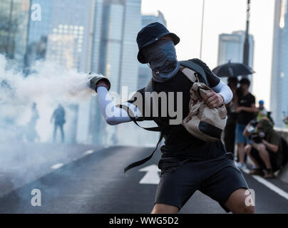 Hong Kong. 15th Sep, 2019. A protester throws a tear gas round back at police during the demonstration.Thousands of protesters marched through the streets on the 15th continuous week of unrest. While the demonstration began peacefully, protesters later faced off against police in front of government offices. Protesters threw bricks and petrol bombs while police attempted to keep the demonstrators at bay by firing dozens of tear gas rounds and blunt projectiles. Riot police eventually deployed vehicles equipped with water cannons and conducted a full dispersal operation. Credit: SOPA Images Lim Stock Photo