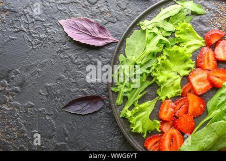 Plate with fresh tasty salad on dark background Stock Photo