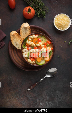 Minestrone Soup. Italian vegetable soup with pasta on dark rustic background, top view, copy space. Healthy vegan vegetarian seasonal meal, homemade m Stock Photo