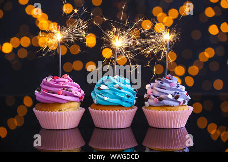 Tasty Birthday cupcakes on table against defocused lights Stock Photo