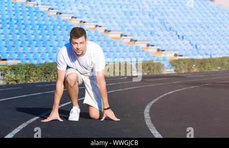 Sporty man in crouch start position at the stadium Stock Photo