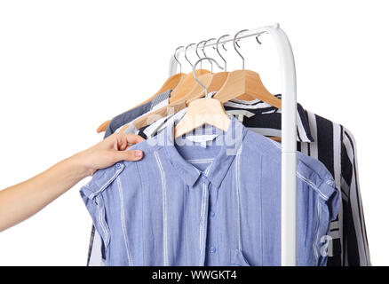 Woman choosing clothes hanging on rack against white background Stock Photo