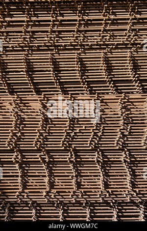 Reinforcing bars with a periodic profile in the packs are stored in the metal products warehouse, close up. Steel materials, construction supplies. Stock Photo