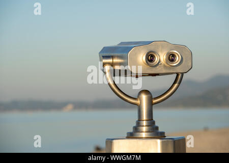 Public binocular on sea shore, close up. Coin operated binocular viewer on blurred background of sunset and sea. Batumi, Georgia Stock Photo