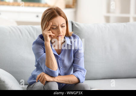 Stressed woman sitting on sofa at home Stock Photo