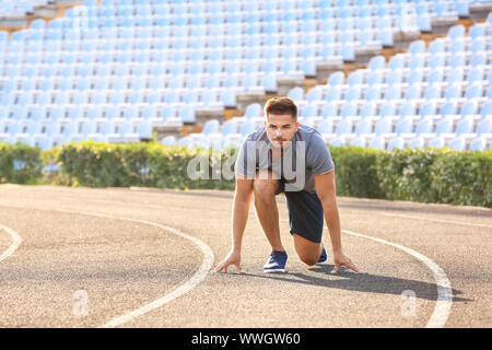 Sporty man in crouch start position at the stadium Stock Photo