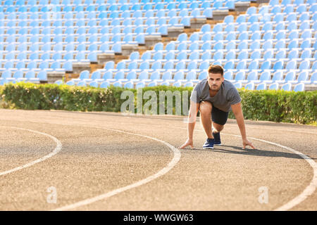 Sporty man in crouch start position at the stadium Stock Photo