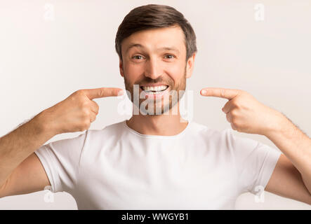 Happy Man Pointing Fingers At His Perfect Smile, White Background Stock Photo