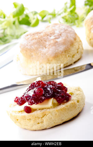 scone spread with butter and cranberry jam Stock Photo