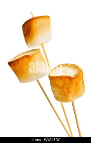 Three golden toasted marshmallows on wooden skewers Stock Photo