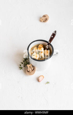 Mushroom Soup. Homemade champignons cream soup with croutons in enamel mug. Healthy and comfort food concept, copy space. Stock Photo