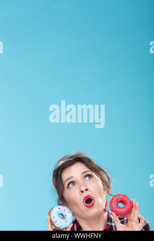 Junk food, diet and unhealthy lifestyle concept - pin-up woman with doughnuts over the blue background Stock Photo