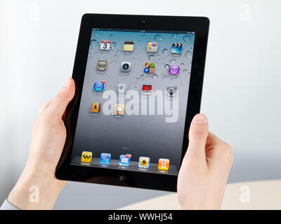 Kiev, Ukraine - December 03, 2011 - Man hands holding Apple iPad2 with homepage on a screen. This second generation iPad2 is designed and development Stock Photo