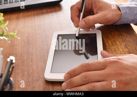 Businessman using white tablet with black screen in office. Horizontal composition. Top view Stock Photo