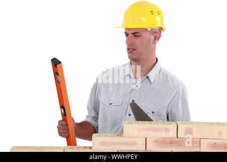 mason holding a level and a trowel Stock Photo