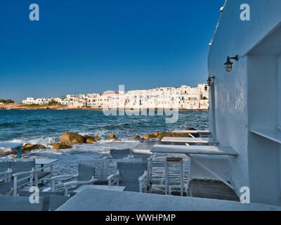 Picturesque view of blue sea empty restaurant and houses on coast in old port of Naoussa Greece on sunny day Stock Photo