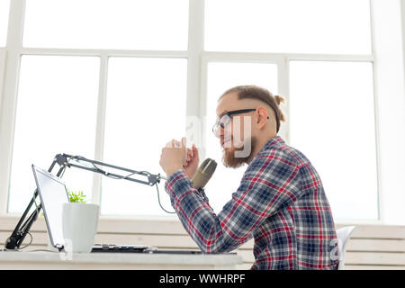 Radio, DJ, blogging and people concept - Smiling man sitting in front of microphone, host at radio Stock Photo
