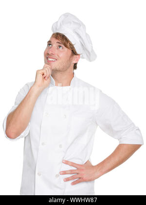Thinking chef, baker or male cook. Young man in chefs whites uniform smiling happy looking up. Portrait of young chef in his twenties. Stock Photo