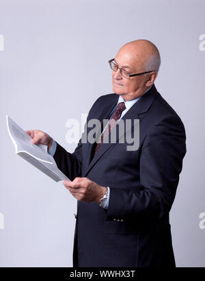 portrait of a successful senior man with book on gray background Stock Photo