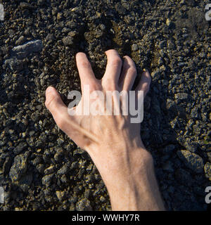 Man's hand clinging stony ground Stock Photo