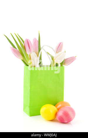 Colored easter eggs with bouquet tulips in green paper bag Stock Photo