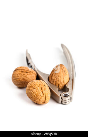 three walnuts and nutcracker on white background Stock Photo