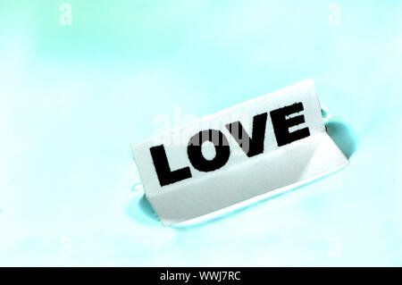 Card floating on water surface with printed word: LOVE Stock Photo