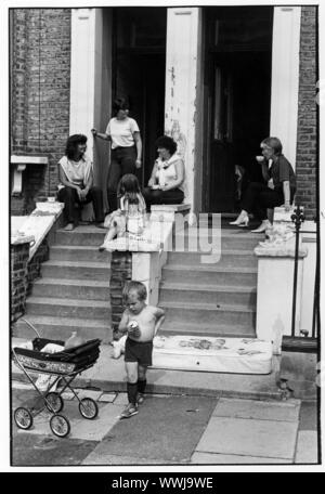 1970's women with children sitting on steps of houses in West London Stock Photo