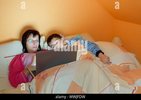 Portrait of a mother and her son using laptop while lying on the bed at home Stock Photo