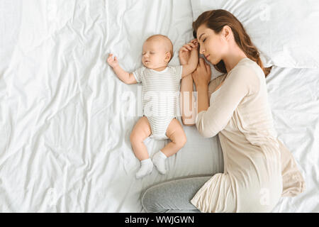 Mother and her adorable newborn baby sleeping in bed together Stock Photo