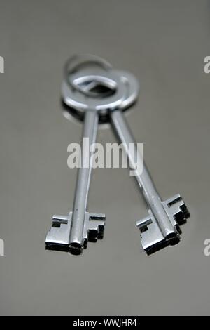 Silver pair of keys over mirror stainless steel real state concept Stock Photo
