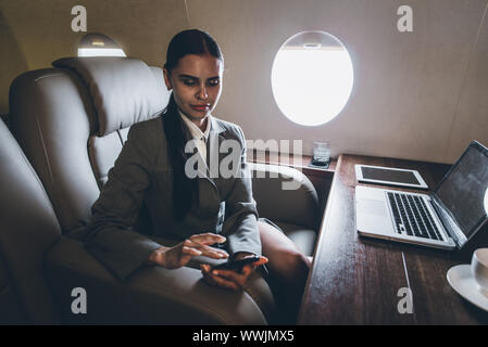 Business woman traveling and working on the private jet Stock Photo