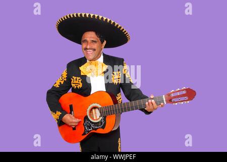 Charro Mariachi singing playing guitar on purple background Stock Photo