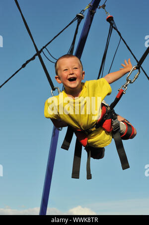 Little boy  jumping on the trampoline (bungee jumping). Stock Photo