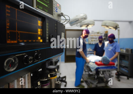 Team work with doctors, nurses, surgeons performing surgery on sick patient in hospital operation room. Focus on foreground Stock Photo