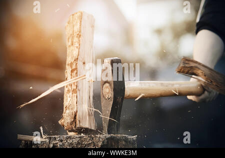 A powerful sharp axe cuts a log into pieces, from which small and large splinters fly in all directions. Stock Photo
